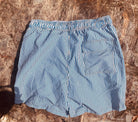 Backside of the Loa swimming shorts. White with blue stripes. Zipped pockets. 