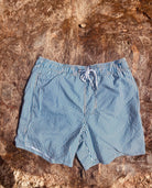 Front side of the Loa swimming shorts with blue with stripes. Zipped pockets. 